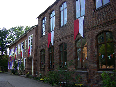 Die Rote Schule hat ihren Namen durch die Farbe der roten Backsteine. Man sieht sie auf dem Foto mit rot - wei&szlig;en Fahnen zur Einschulungsfeier geschm&uuml;ckt