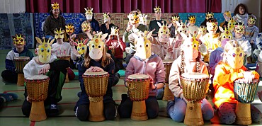 Kinder mit Giraffenmasken auf dem Kopf während des Trommelprojekts