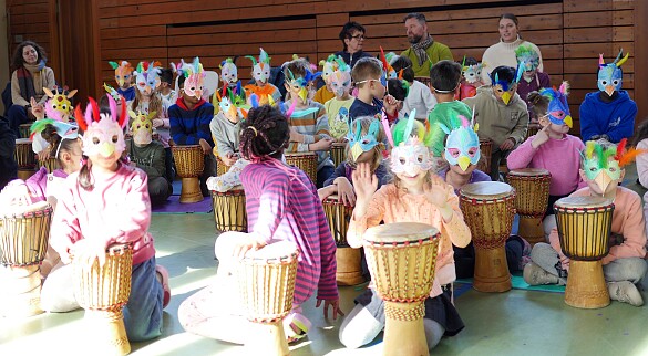 Kinder mit Vogelmasken auf dem Kopf während des Trommelprojekts