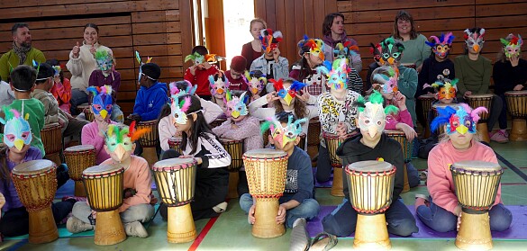 Kinder mit Vogelmasken auf dem Kopf während des Trommelprojekts