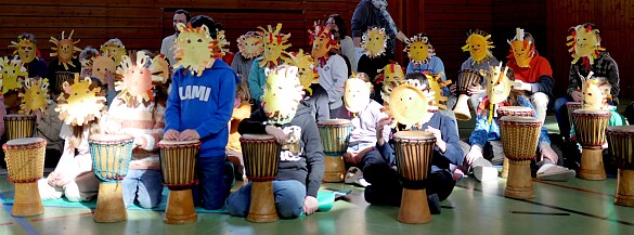 Kinder mit Löwenmasken auf dem Kopf während des Trommelprojekts