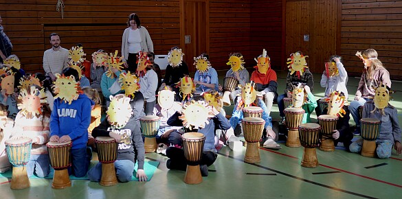 Kinder mit Löwenmasken auf dem Kopf während des Trommelprojekts