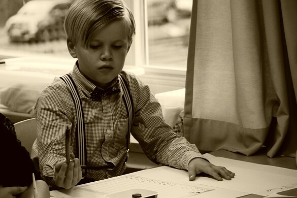 ein Junge in alter Schulkleidung sitzt im Unterricht